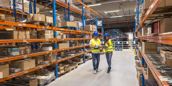 Twee Warehousemedewerkers Bespreken Logistieke Processen In Een Distributiecentrum.